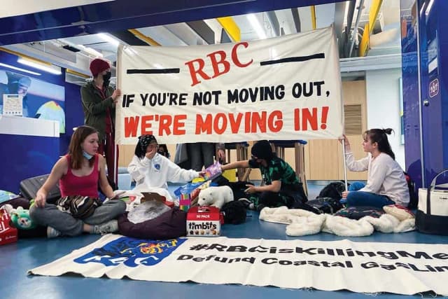 Students staging a sit-in with banners demanding fossil fuel divestment.